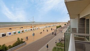 Een boulevard aan het strand met een rij strandhuisjes, een pad en uitzicht op het strand en de oceaan.