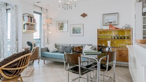 Un salon moderne comprenant un canapé, des fauteuils, une table basse, une bibliothèque et un coin repas.