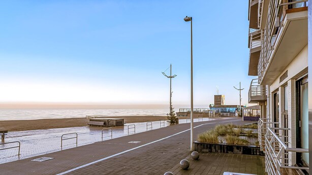 Une promenade en bord de mer offrant une vue dégagée sur l’océan, un sentier pavé et un bâtiment doté de balcons.