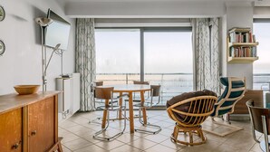 Un salon moderne avec une grande fenêtre, une table ronde et une bibliothèque.