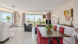 Een moderne hotelkamer met een zithoek, een bank, een televisie en uitzicht op zee.