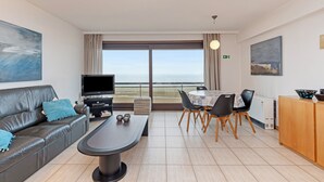 Un salon moderne comprenant un canapé, une table basse, un téléviseur et un coin repas avec des chaises et une table.