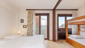 Une chambre avec deux lits, une fenêtre et une porte donnant sur un balcon.