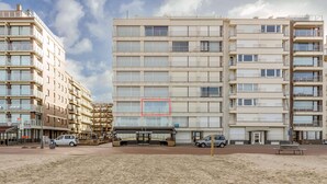 A multi-story building with a central entrance, surrounded by a sandy area. - 3 bedroom accommodation in Oostduinkerke (Oostduinkerke)