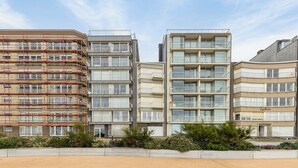 A multi-story residential building with balconies, a gated entrance, and a landscaped area with shrubs. - 2 bedroom accommodation in Koksijde (Koksijde)