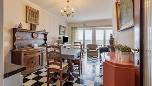 A dining area with a checkered floor, wooden furniture, and a chandelier. - 2 bedroom accommodation in Koksijde (Koksijde)