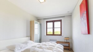 A bedroom with a large bed, a wardrobe, a window, and a bedside table. - Zonnehaven II E 0209+G47* (NIEUWPOORT)