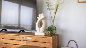 A wooden TV stand with a flat-screen TV, a decorative vase with green plants, and a small pineapple. - Zonnehaven II E 0209+G47* (NIEUWPOORT)