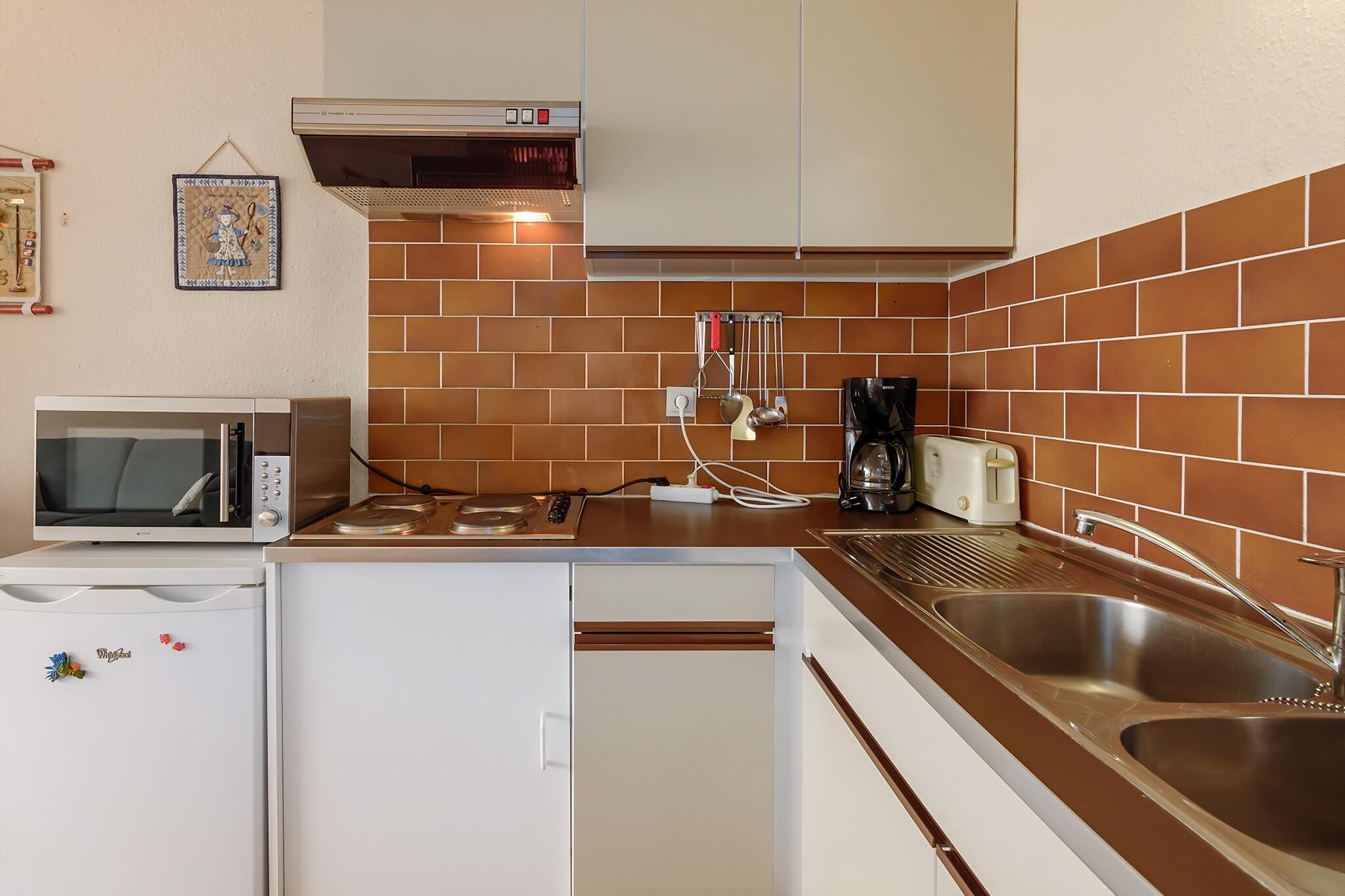 Una cocina compacta con microondas, tostadora y lavamanos.