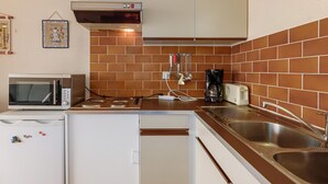 Een compacte keuken met een magnetron, broodrooster en spoelbak.