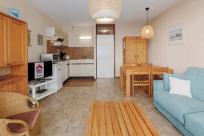 A compact living space with a kitchenette, a dining area, and a seating area with a sofa and chairs.