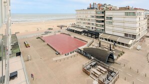 Een strandhotel met een groot rood zwembad, buitenzitplaatsen en uitzicht op de oceaan.