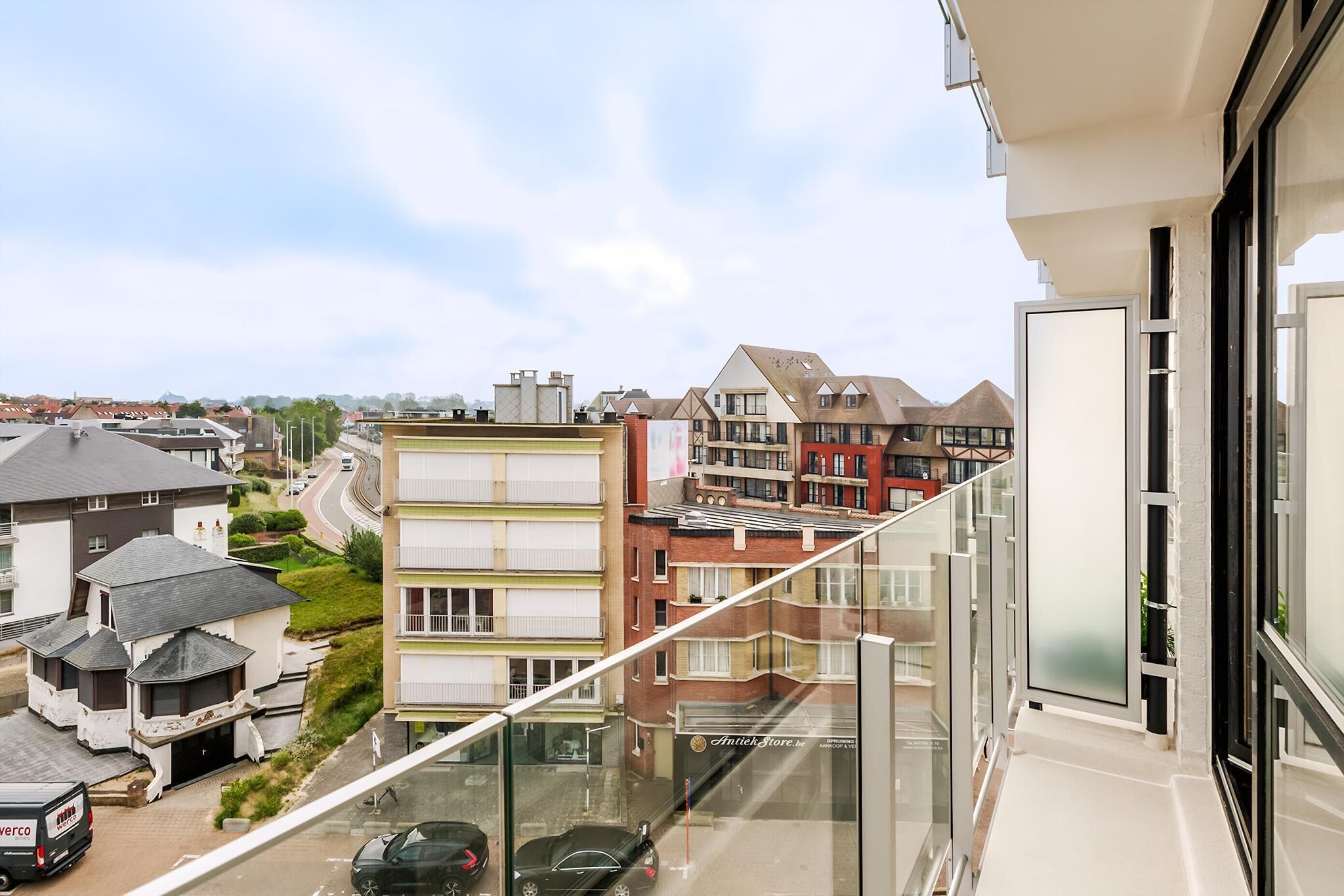 A high-rise building with a glass balcony overlooking a residential area.