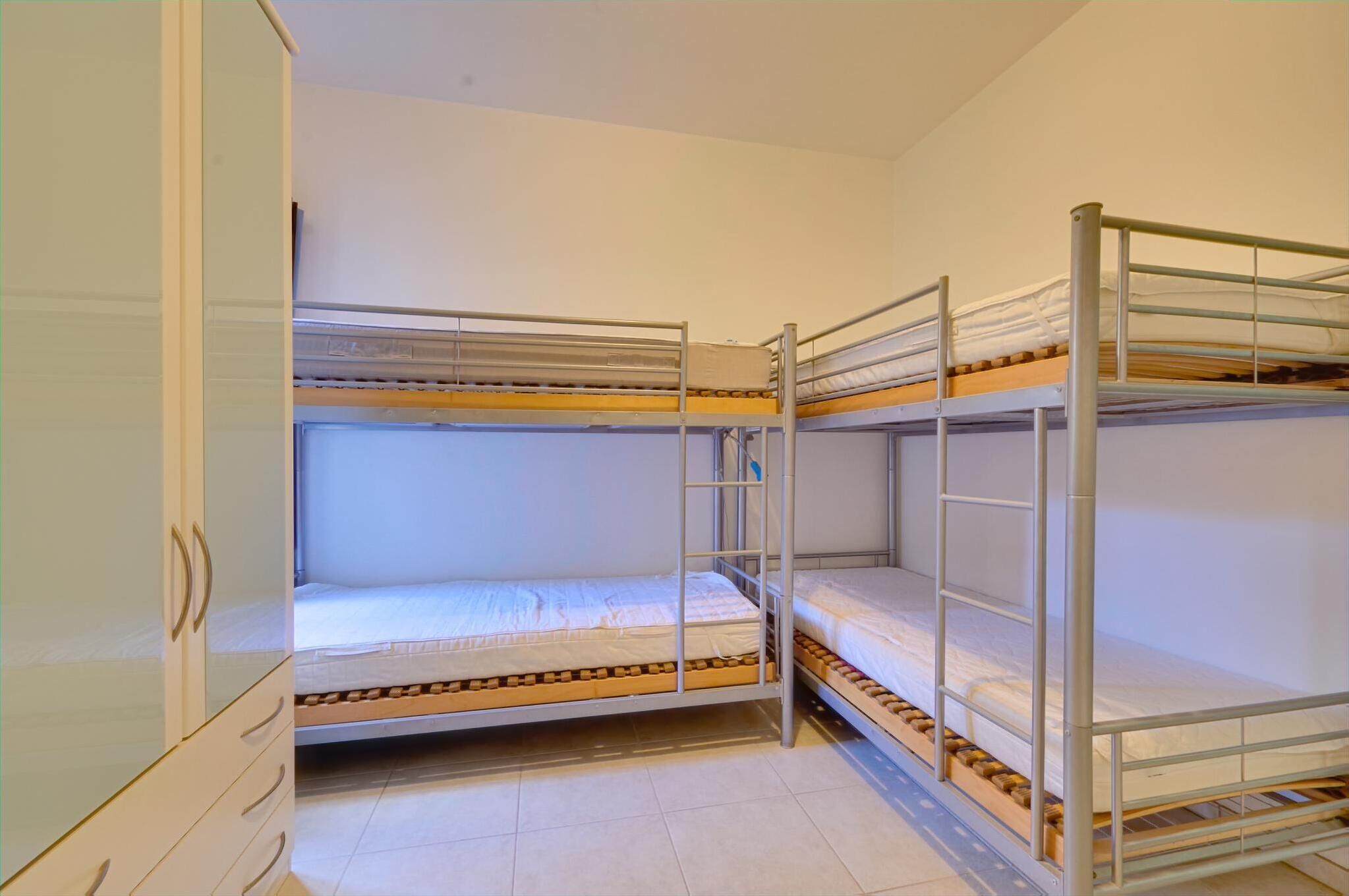 A bunk bed room with a wardrobe and a small table.