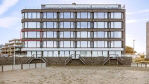 A multi-story building with a modern architectural design, featuring a series of large windows and a stone facade. - Idesende 2/0203 + P* (Sint Idesbald)