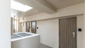 A hallway with a central column, a large wooden door, and a small window. - Hotel Living Inn Kenchoumaeeki (Naha)