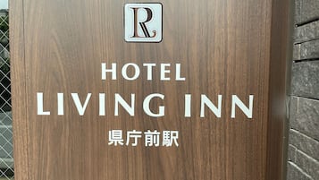 A wooden sign with the text "HOTEL LIVING INN" and a logo above it.