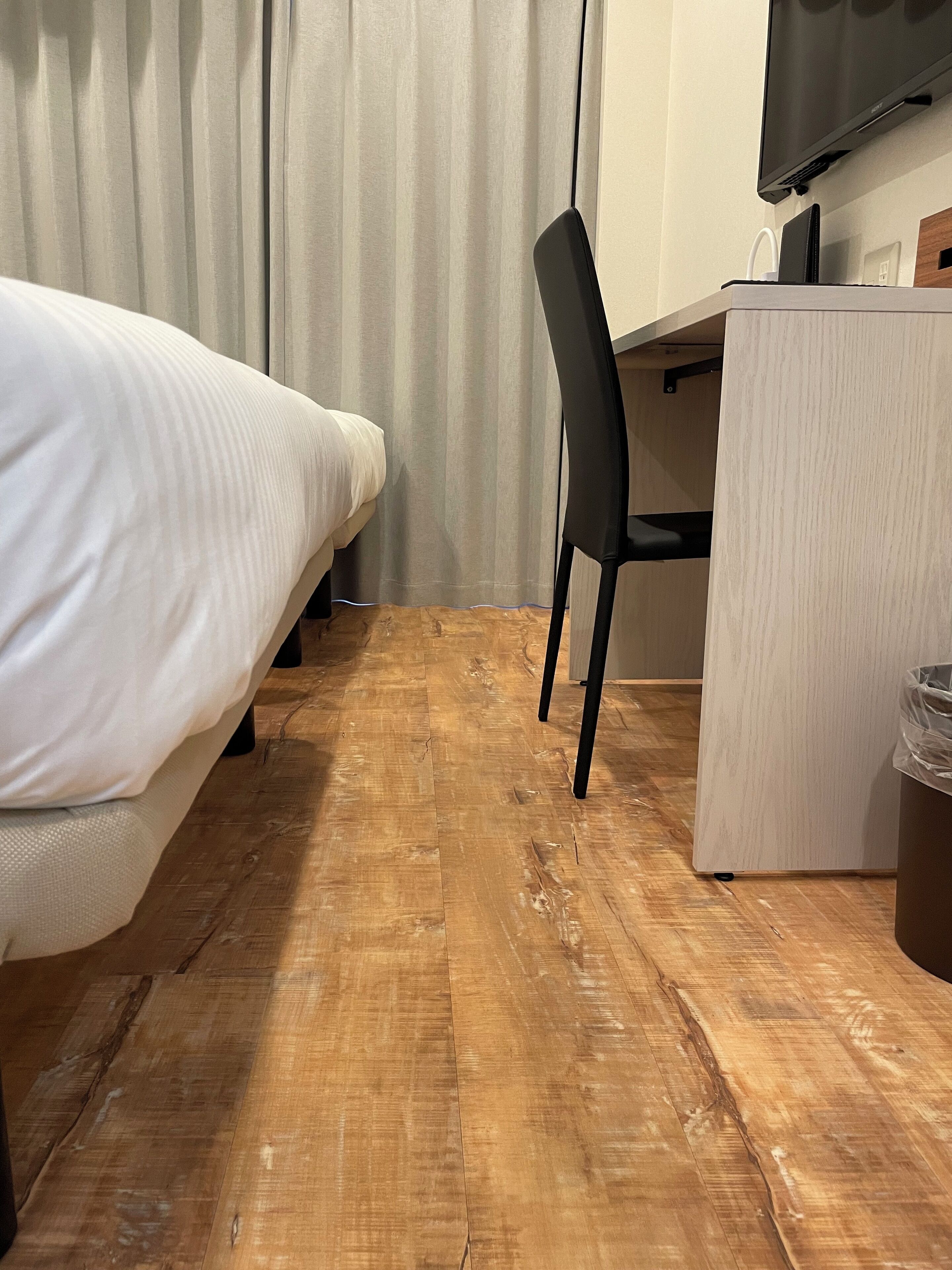 A hotel room with a bed, a desk, a chair, and a television.