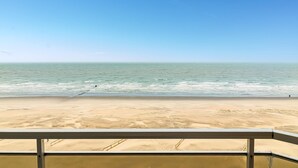 Une vue sur la plage depuis un balcon doté d’une balustrade.