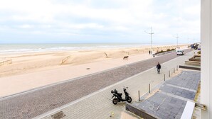 Un sendero pavimentado junto a una playa arenosa, con una moto estacionada al lado.