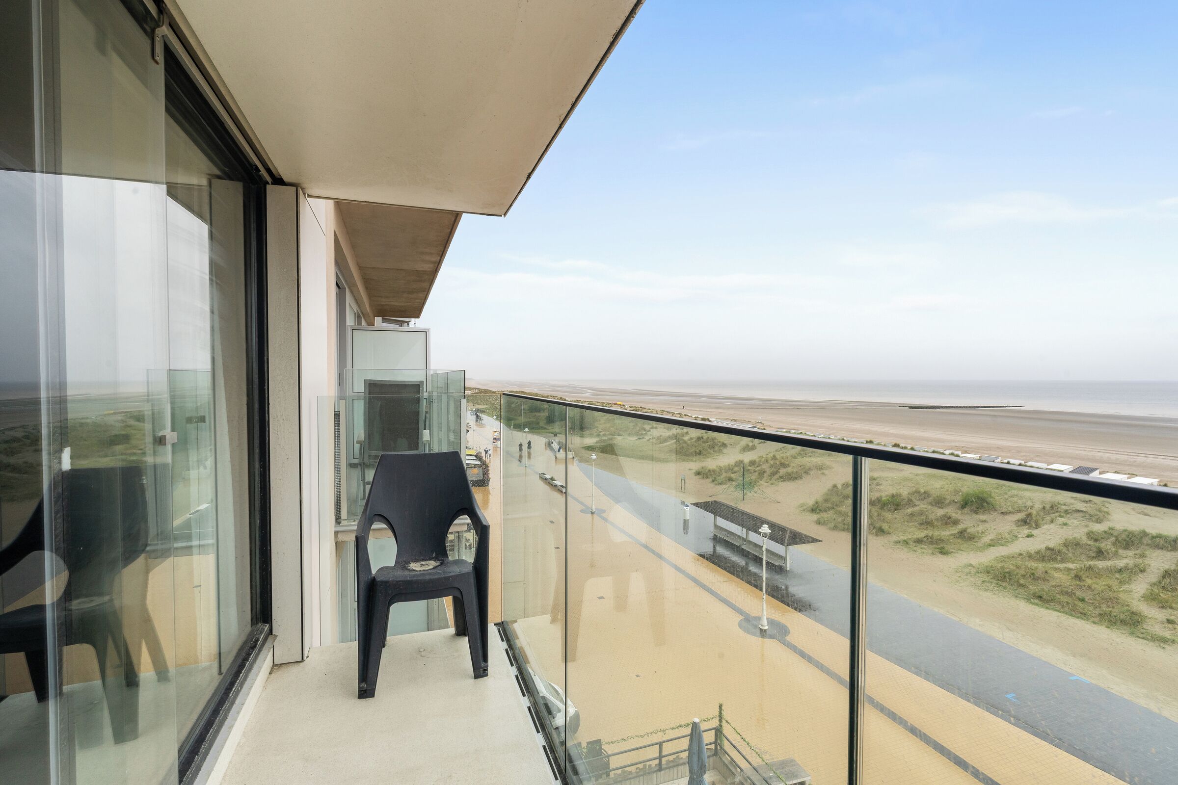 Un balcon avec vue sur la plage et une chaise.