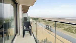 Un balcon avec vue sur la plage et une chaise.