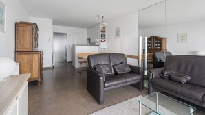 Un salon moderne avec un canapé, une table basse en verre et un meuble en bois.