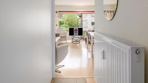 Ein modernes Interieur mit einer Diele, die in einen Essbereich führt, inklusive Fernseher, Stühle und Heizkörper.