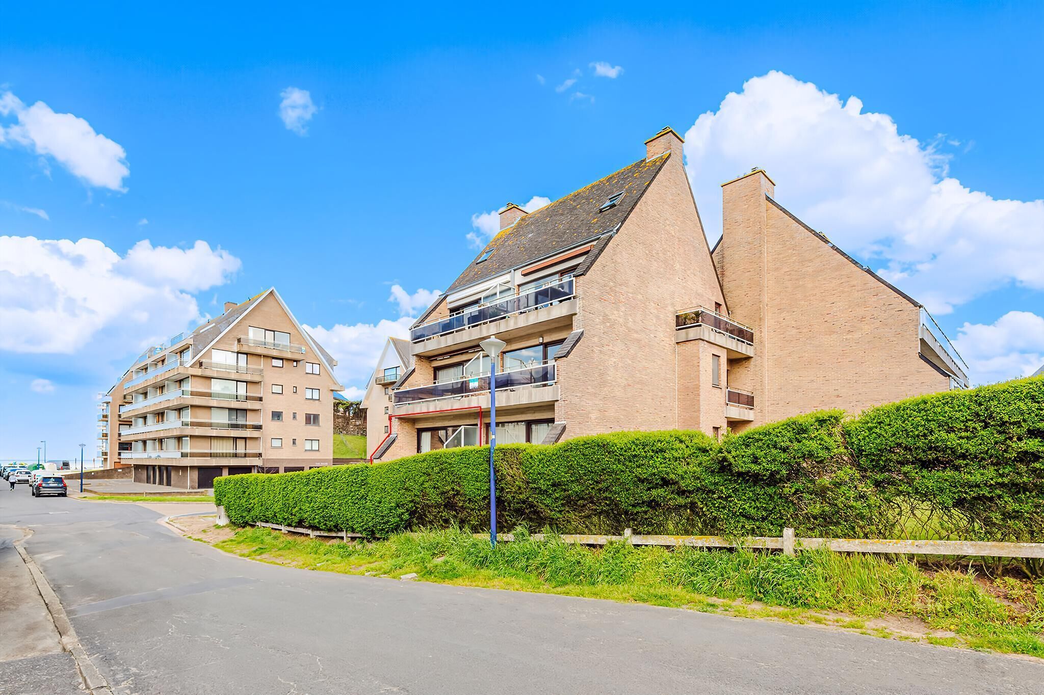 Een modern appartementencomplex met meerdere balkons en een helderblauwe lucht.