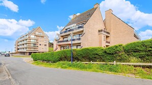 Ein modernes Apartmenthaus mit mehreren Balkonen und wolkenlosem, blauem Himmel.