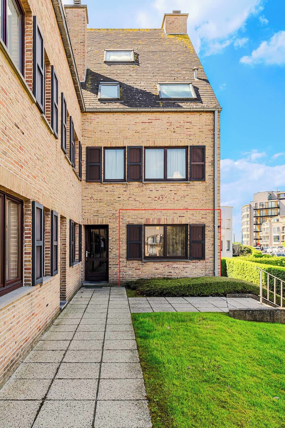 A two-story brick building with a flat roof, multiple windows, and a paved entrance area.