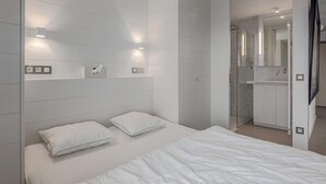 A modern bedroom with a large bed, two pillows, a bedside table, and a nightstand. - Den Oever V 0106 met parking (Nieuwpoort)