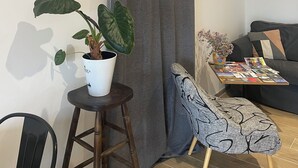 A living room with a grey curtain, a potted plant, a sofa, and a small table with magazines. - Guest House : Lo Refugi  (Pechbonnieu)