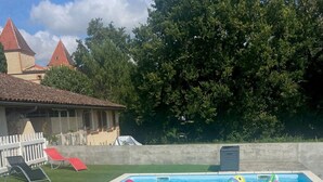 A swimming pool with two inflatable toys, a white fence, and a building with red roofs in the background. - Guest House : Lo Refugi  (Pechbonnieu)