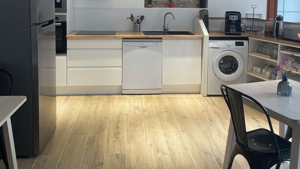 A modern kitchen with a dishwasher, washing machine, and a wooden countertop. - Guest House : Lo Refugi  (Pechbonnieu)