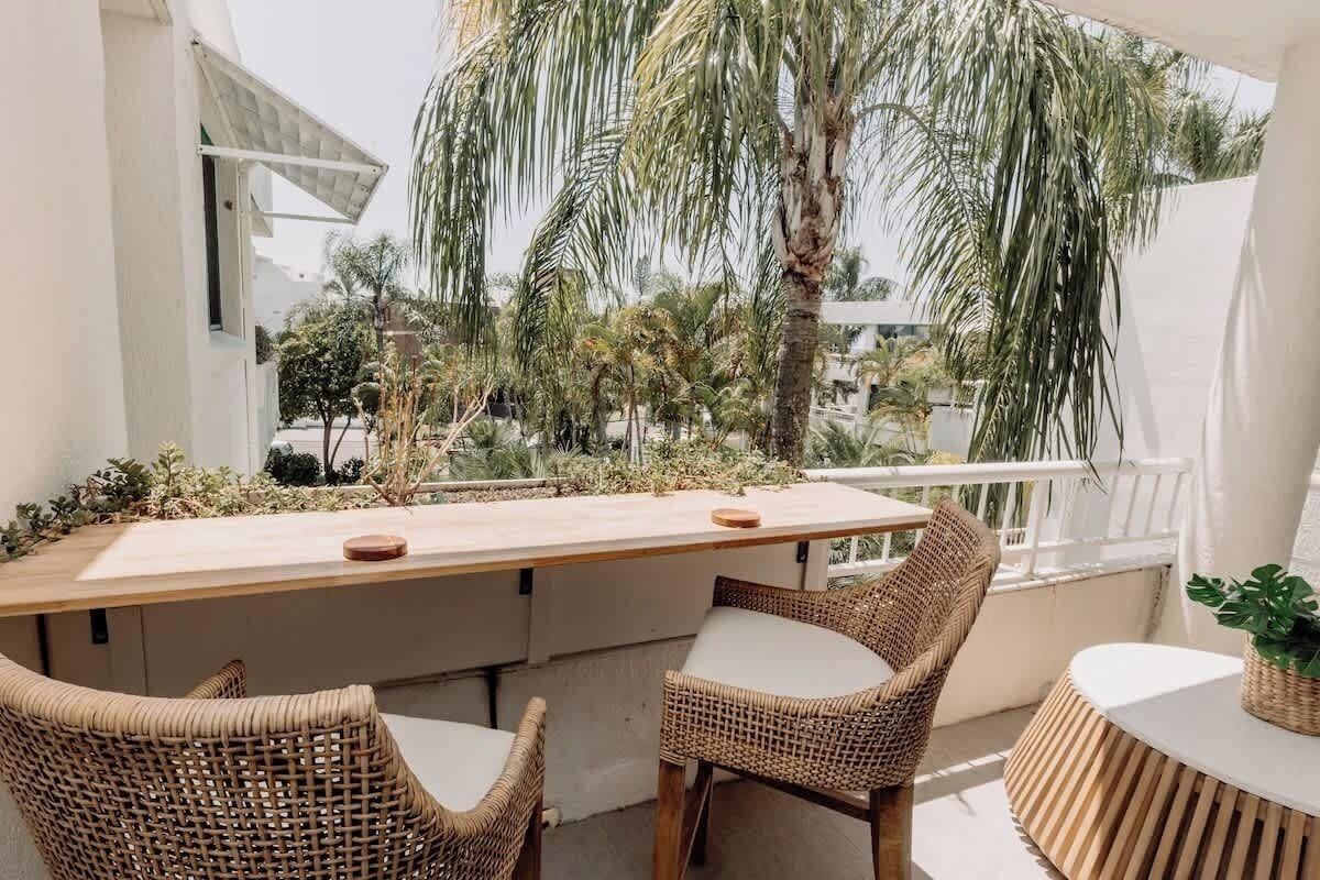 Relax on the balcony with tropical palm views, overlooking the pool and glimpses of the ocean – your perfect getaway spot awaits!