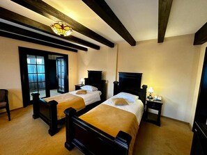 A room with two beds, wooden headboards, a chandelier, and a small table with a lamp. - Podu' Cu Lanturi  (Bacau)