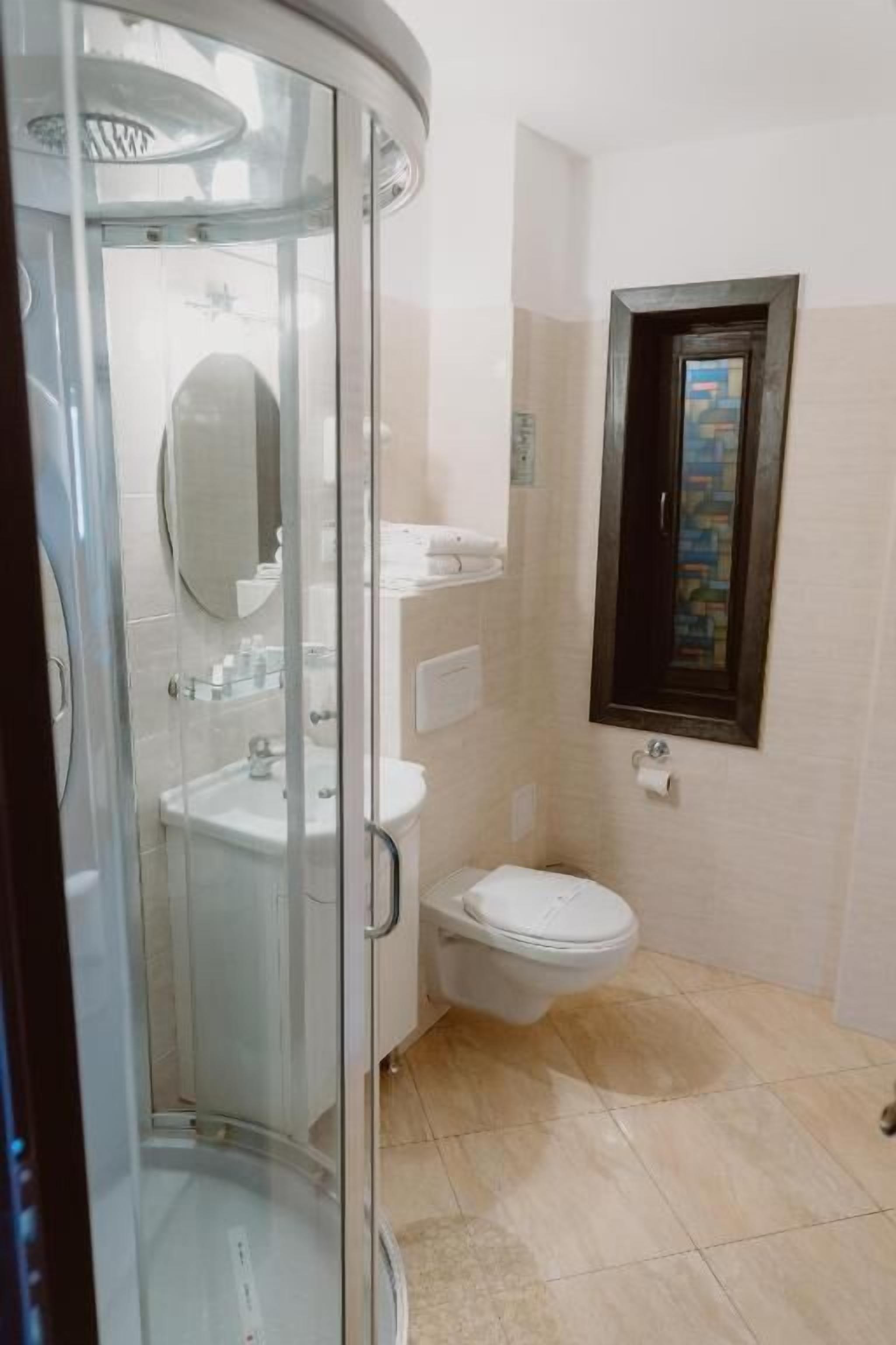 A bathroom with a glass shower enclosure, a toilet, and a sink.