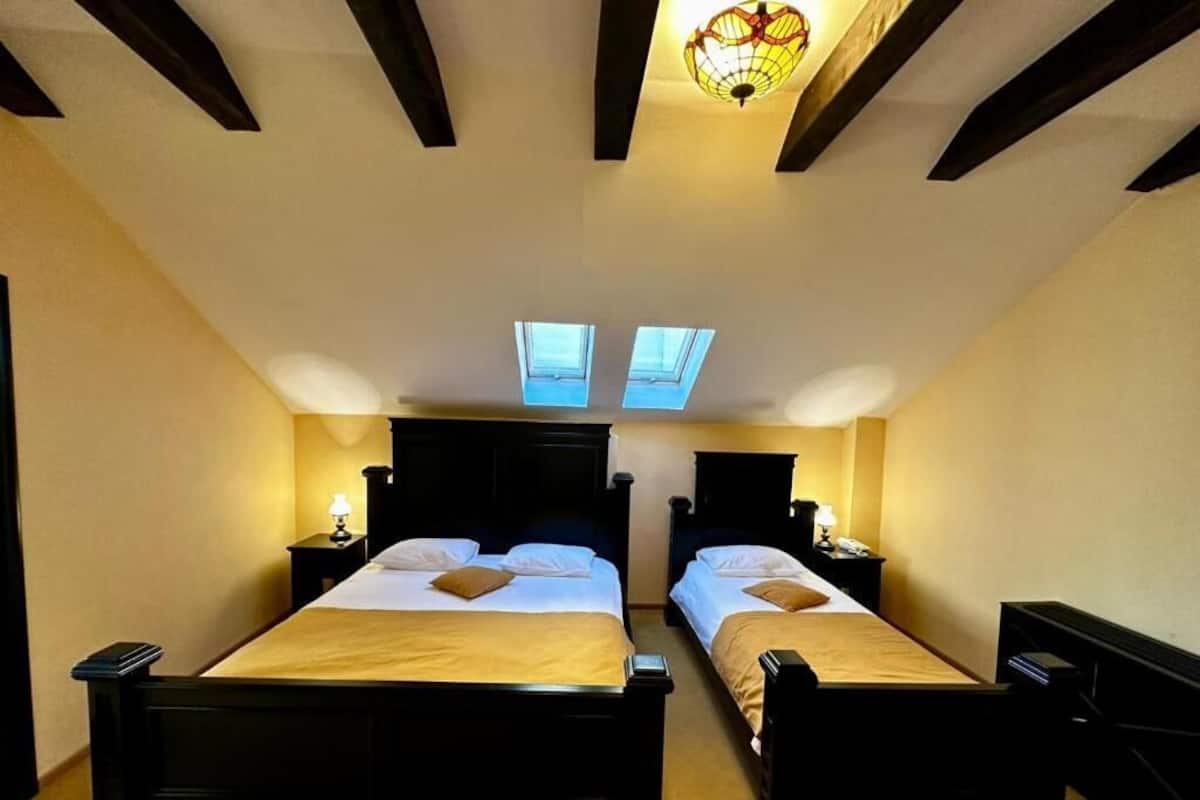 Quarto com duas camas, ventoinha no teto e claraboias.