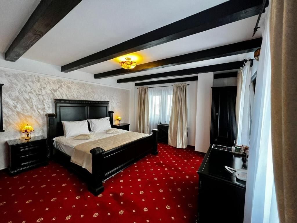 Ein Schlafzimmer mit einem großen Bett, einem dunkelholzigen Kopfteil, einem roten Teppich mit Muster und einer Wand aus weißem Marmor.