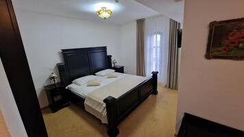 A bedroom with a large bed, a nightstand, a lamp, and a painting on the wall.
