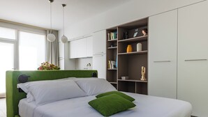 Une chambre moderne avec une tête de lit verte, du linge de lit blanc et un coussin vert.