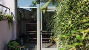 Un bâtiment moderne doté d’une porte en verre, d’un escalier et d’une végétation luxuriante.