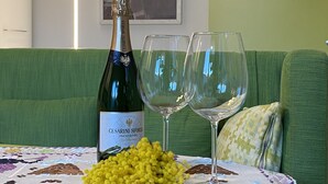 Une bouteille de vin Cerasari Sforza, deux verres et un bouquet de fleurs jaunes sont posés sur une table dans une pièce où se trouvent un canapé vert et un tableau encadré accroché au mur.