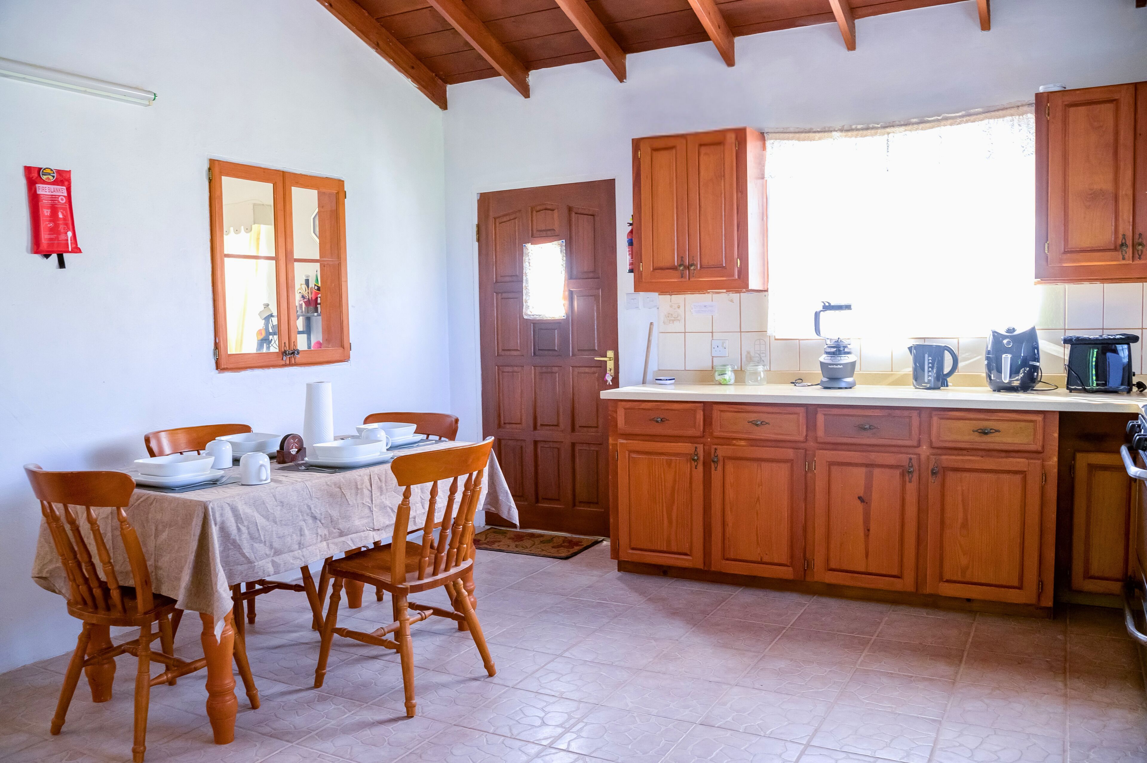 A kitchen with wooden cabinets, a dining table with chairs, and a window.