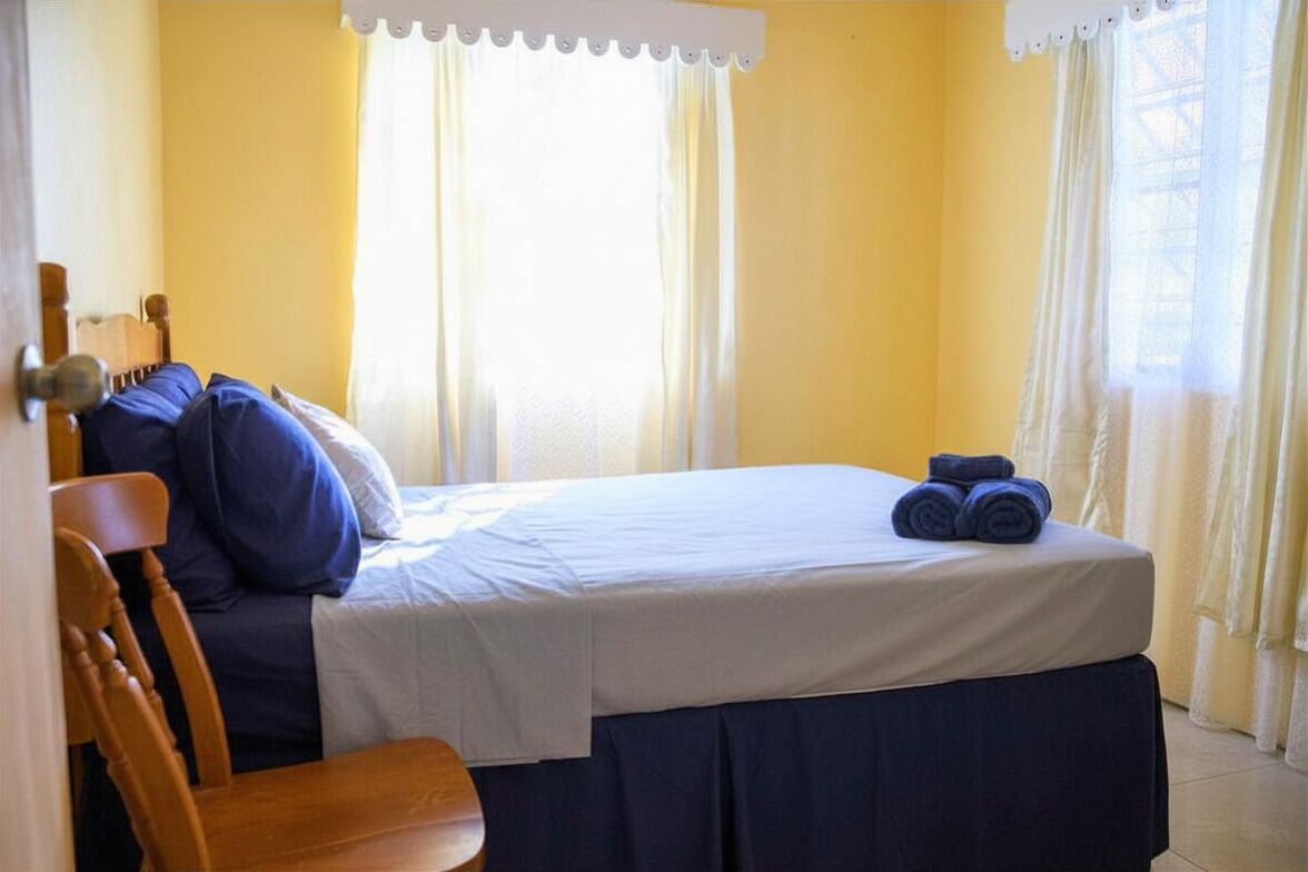 A bedroom with a bed, a chair, and a window with curtains.