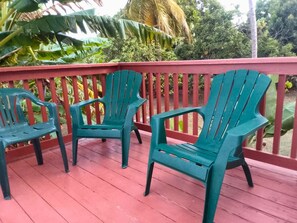 Three green chairs on a red deck with a red railing.