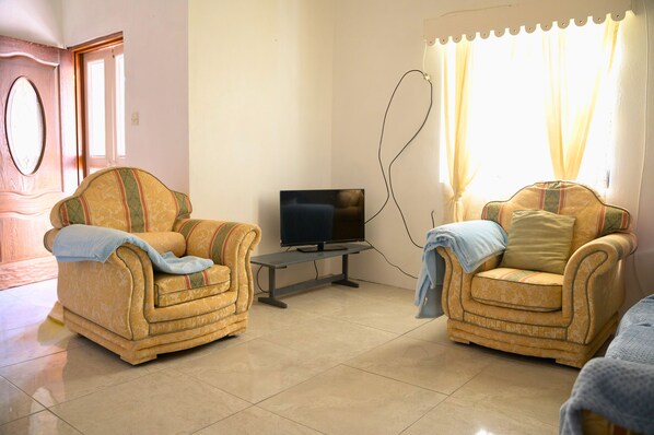 A living room with two armchairs, a television, and a small table.