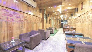 A restaurant with wooden walls, cushioned seating, and tables. - Hotel The Grand Majestic (Jaipur)