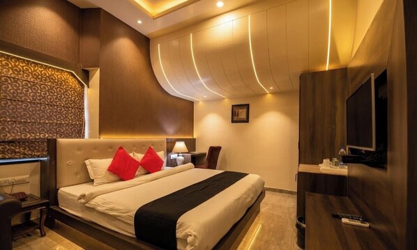 Ein Hotelzimmer mit Bett, Nachttisch, Lampe, Fernseher und Wand-Fernseher.